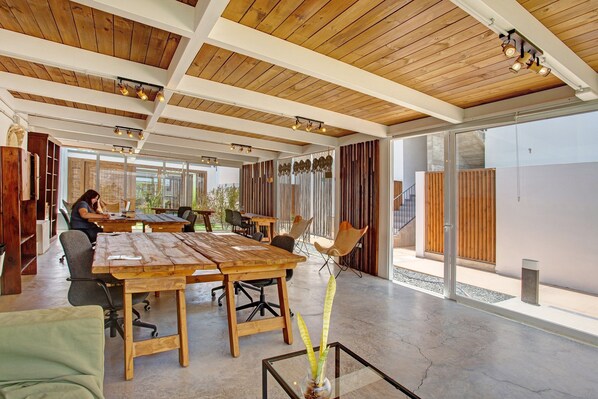 Una habitación amplia con techo de madera, ventanas grandes y una mesa con sillas.