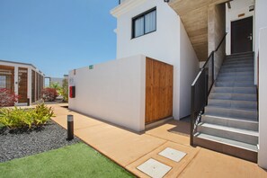 Een modern gebouw met een trap, een houten deur en een kleine tuin met planten.