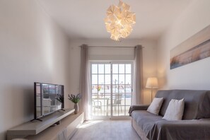 Una sala de estar moderna con un sofá, televisor y un balcón con vistas.
