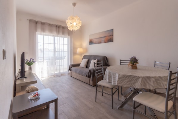 Una sala de estar moderna con un sofá, una mesa de comedor, sillas, una lámpara y una planta decorativa.
