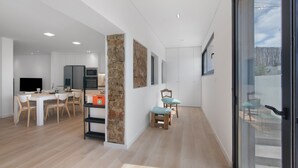 Una cocina moderna con armarios blancos, horno empotrado y comedor con mesa y sillas.