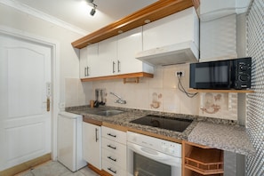 A kitchen with white cabinets, a granite countertop, a built-in microwave, and a dishwasher.