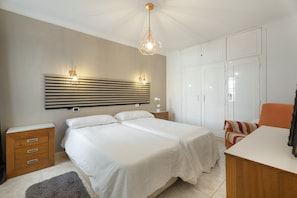 A bedroom with a bed, bedside tables, a desk, and a wardrobe.