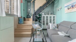 A living room with a sofa, a glass coffee table, a chair, a staircase, and a cabinet.