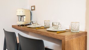 Una mesa de madera con una cafetera, dos tazas y un vaso encima.