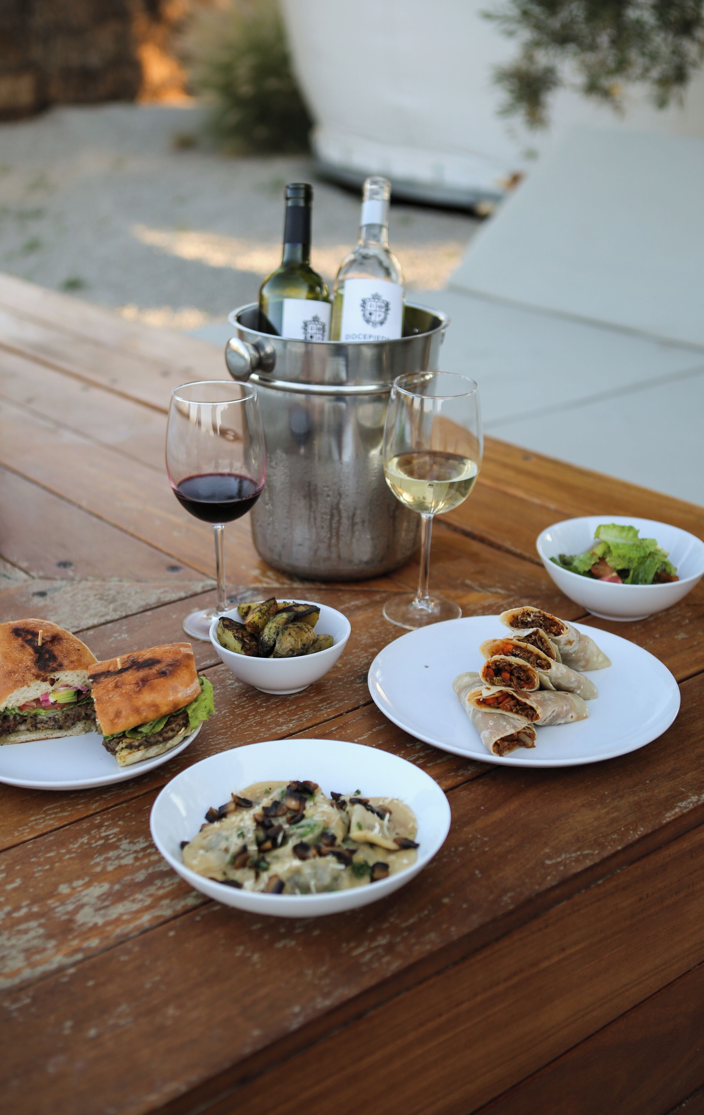 A wooden table with various dishes, a wine bottle, and glasses.