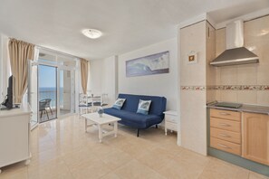 Una sala de estar moderna con un sofá, una mesa de comedor y una zona de cocina con armarios y una estufa.