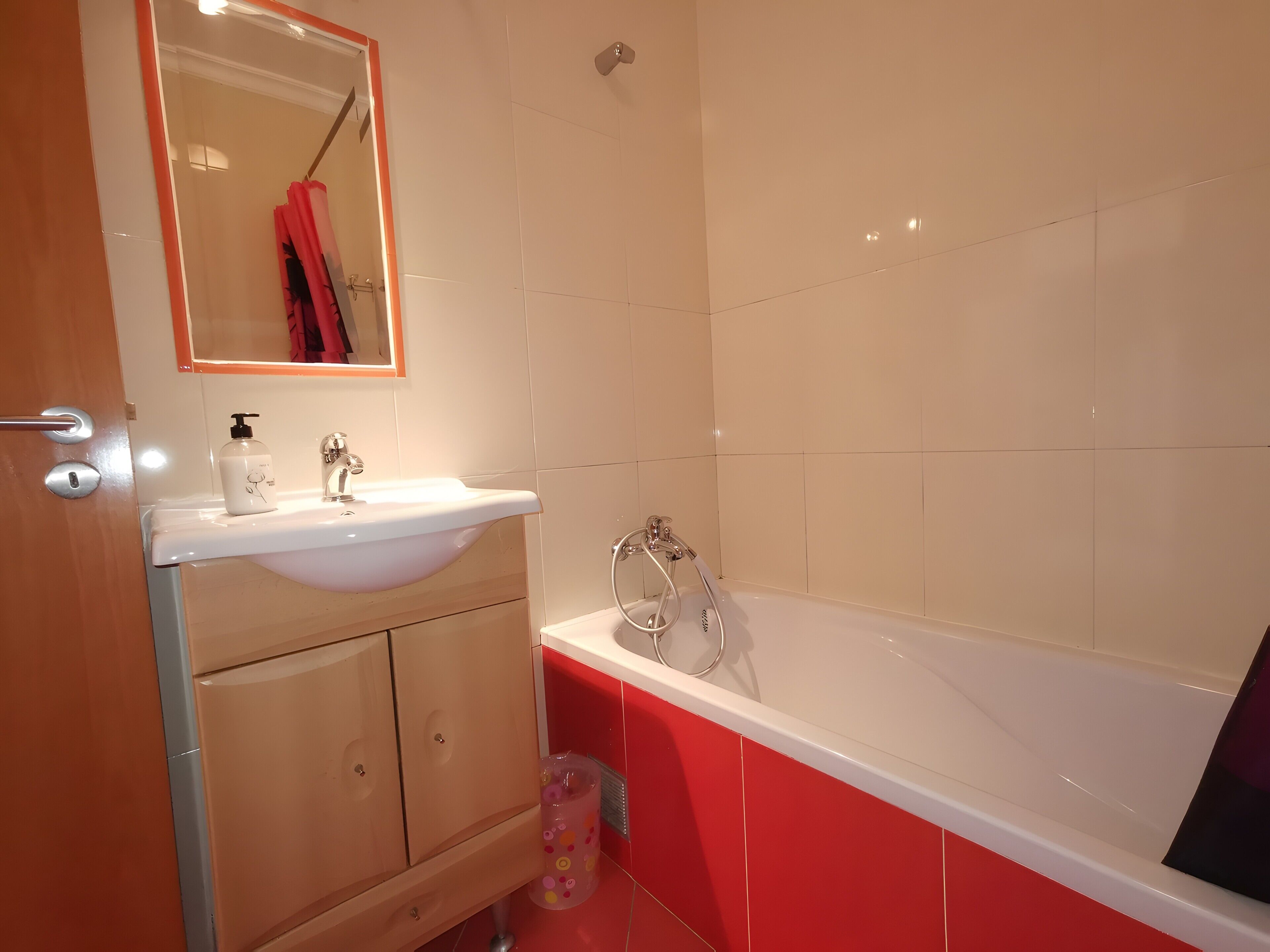 A bathroom with a sink, mirror, and bathtub.