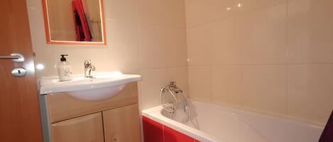 A bathroom with a sink, mirror, and bathtub.