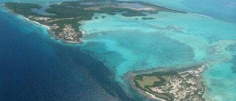 An aerial view of a tropical island with clear turquoise waters and several small islets.