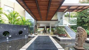 A modern building with a covered walkway, a stone wall with circular cutouts, and a statue. - Yeguas U6 by Wynwood House (Anapoima)