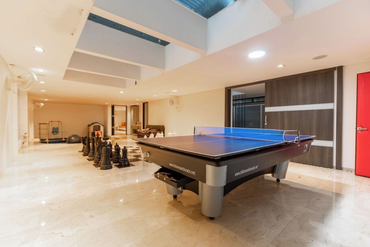 Un grand espace intérieur comprenant une table de ping-pong, un jeu d’échecs et une porte rouge.