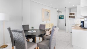 Cocina moderna con armarios blancos, cafetera y zona de comedor con una mesa redonda y sillas.
