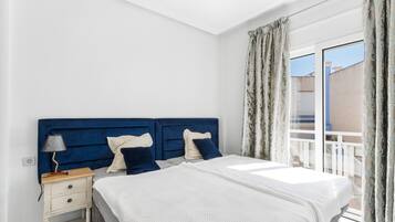 A bedroom with a bed, nightstand, lamp, and curtains.