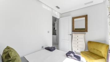Een slaapkamer met een bed, een kaptafel, een stoel, een spiegel en een deur naar een badkamer.