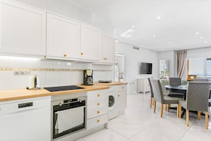 Une cuisine moderne avec des meubles blancs, un plan de travail en bois et un four encastré.