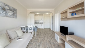 Una sala de estar moderna con un sofá, televisión y estanterías de madera.