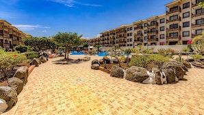 Un patio con suelo de baldosas, una piscina y edificios de varios pisos con balcones.