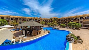 A swimming pool with lounge chairs and a bar area, surrounded by multi-story buildings with balconies. - Vacation 'Atlantic 2 Amazing View' with Sea View, Shared Pool and Wi-Fi (Costa Del Silencio)