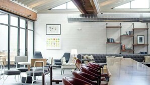 Un espace de détente moderne avec des sièges, une longue table et des étagères.