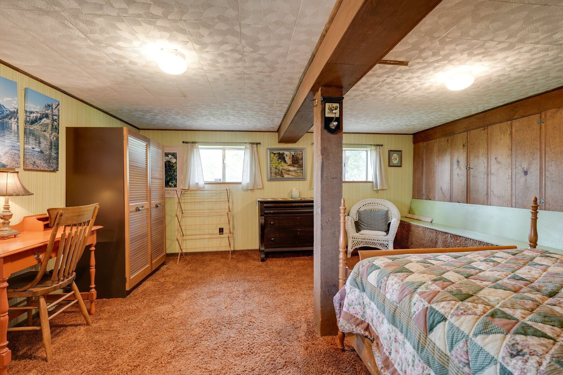 A room with a bed, a desk, a chair, and a dresser.