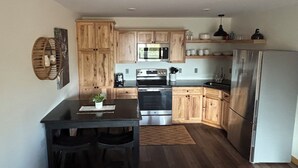 Una cocina moderna con armarios de madera, electrodomésticos de acero inoxidable y una mesa de comedor negra.
