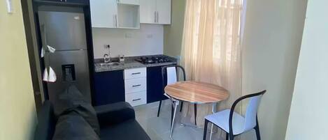 Un espacio habitable compacto con kitchenette, comedor y sofá.