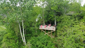 A wooden deck with seating, surrounded by dense greenery and trees. - River side gem of port franks (Port Franks)