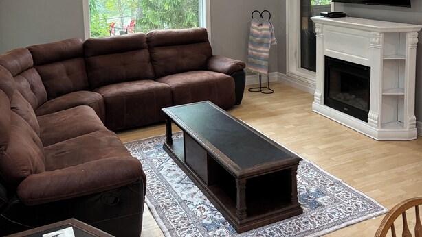A living room with a sectional sofa, a fireplace, a television, and a large window with a view of trees. - River side gem of port franks (Port Franks)