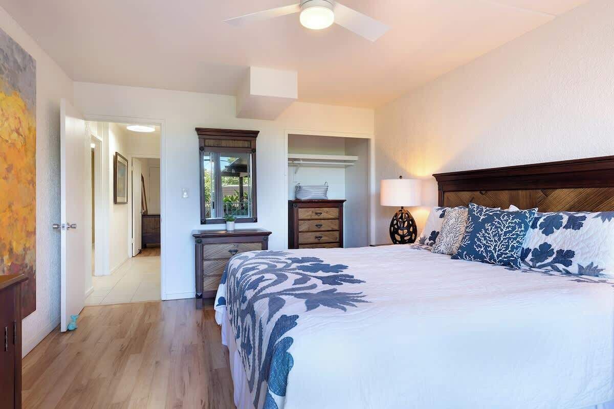 Quarto com uma cama grande, ventilador de teto, cômoda e closet espaçoso.