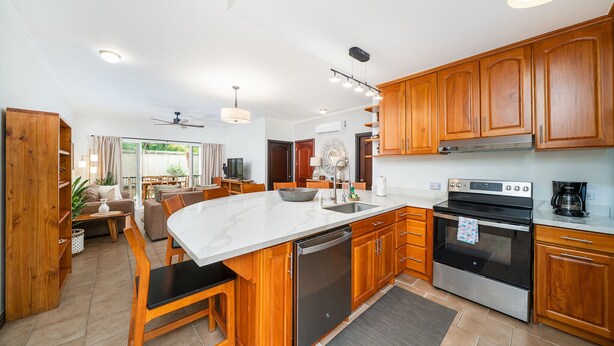 A modern kitchen with wooden cabinets, a stainless steel dishwasher, and a built-in oven.