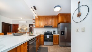 A modern kitchen with wooden cabinets, stainless steel appliances, and a marble countertop.
