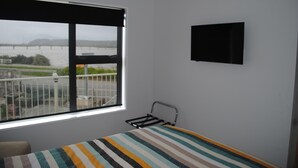 A bedroom with a window offering a view of a bridge and river.