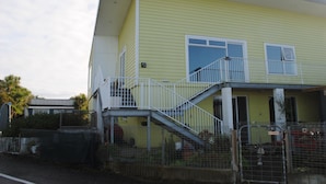 A yellow building with a white balcony and a gated entrance.