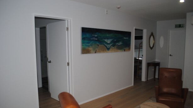 A living room with a brown leather armchair, a small round table, and a painting on the wall.