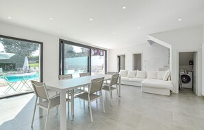Un espace de vie moderne comprenant un coin repas, un canapé et une vue sur une piscine.