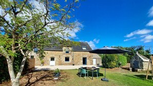 A stone house with a patio, a table, and chairs.