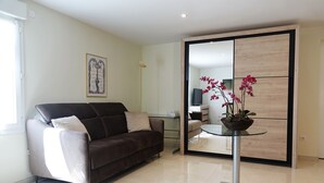 Una sala de estar moderna con un sofá, una mesa de vidrio con una planta en maceta y un piso de baldosas con espejo.