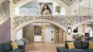 A spacious lobby with stone arches, green sofas, and a view of the kitchen. - Villa Pasiphae - With Private Pool (Garazo)