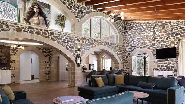 A spacious living area with stone walls, a large sofa, and a television. - Villa Pasiphae - With Private Pool (Garazo)