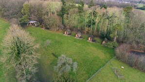 Een landelijk gelegen pand met verschillende kleine huisjes, omgeven door bomen en open velden.