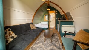 Een gezellig interieur met een bank, een stoel, een vloerkleed en een kitchenette.