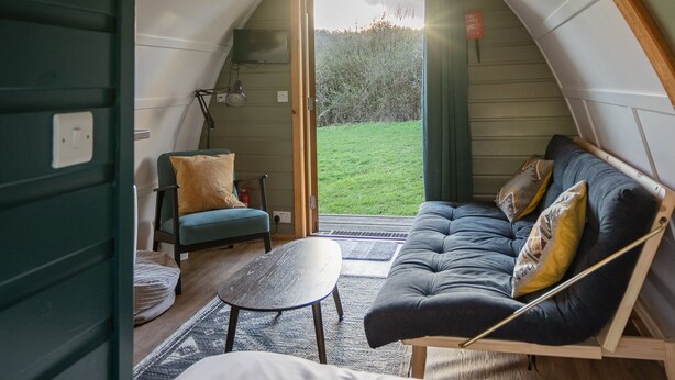 Een gezellig, gebogen interieur met een bank, een kleine tafel en een lamp.