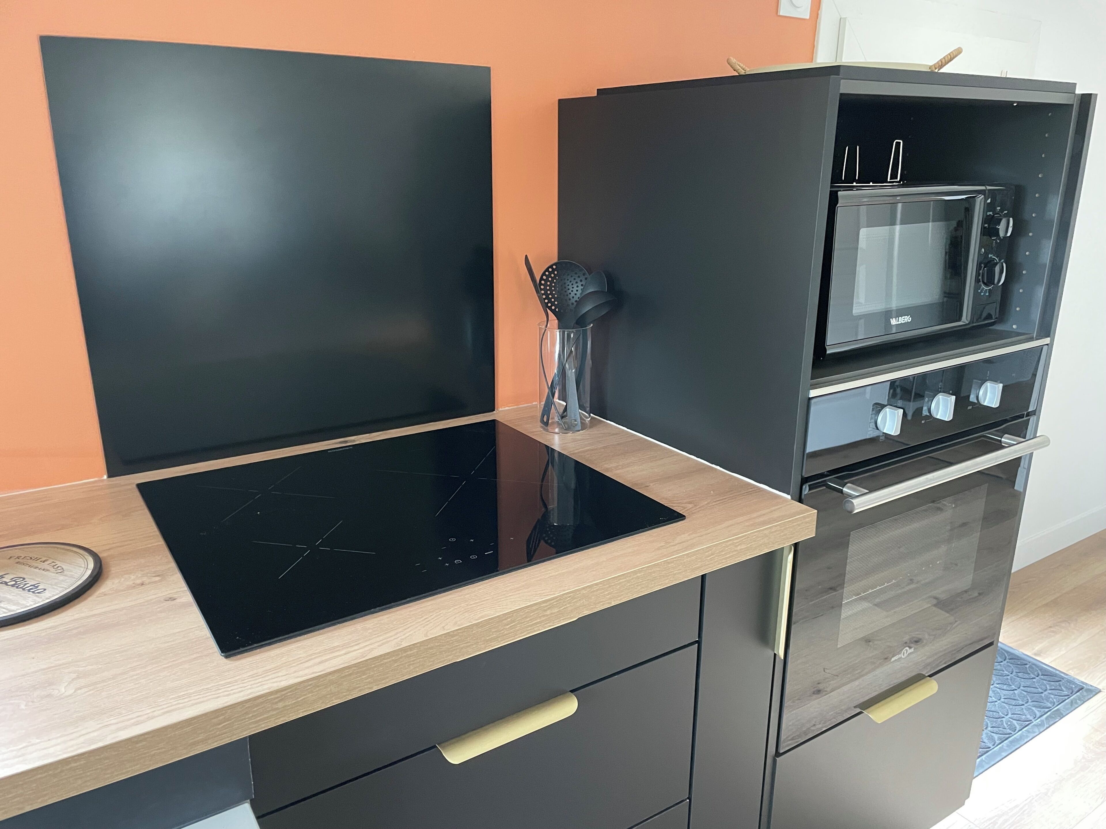Een moderne keuken met een zwart inductiekookveld, een magnetron en een inbouwoven.