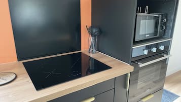 Een moderne keuken met een zwart inductiekookveld, een magnetron en een inbouwoven.
