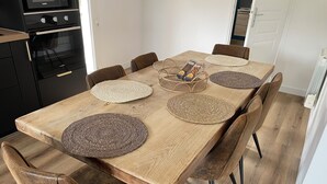 A dining table with woven placemats, six brown upholstered chairs, and a basket of bread on the table.