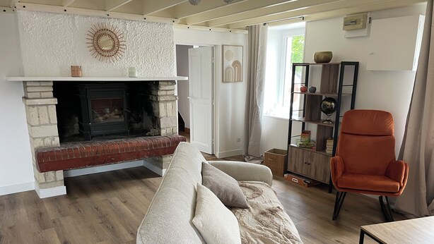 A living room with a fireplace, a sofa, an orange armchair, and a wooden coffee table.