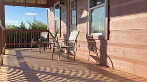 A wooden deck with outdoor furniture, a covered area, and a view of the surrounding trees.