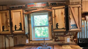 A rustic kitchen with wooden cabinets, a built-in sink, and a window with a view of greenery.