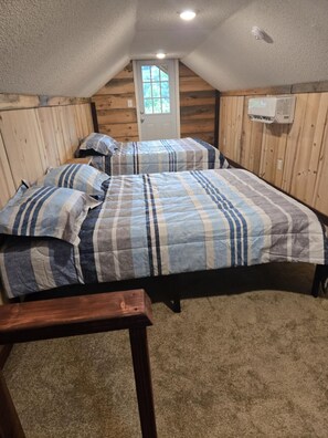 A bedroom with a sloped ceiling, wooden walls, a door, and a bed with striped bedding. - Fabulous cabin with AC in Sevierville (Sevierville)